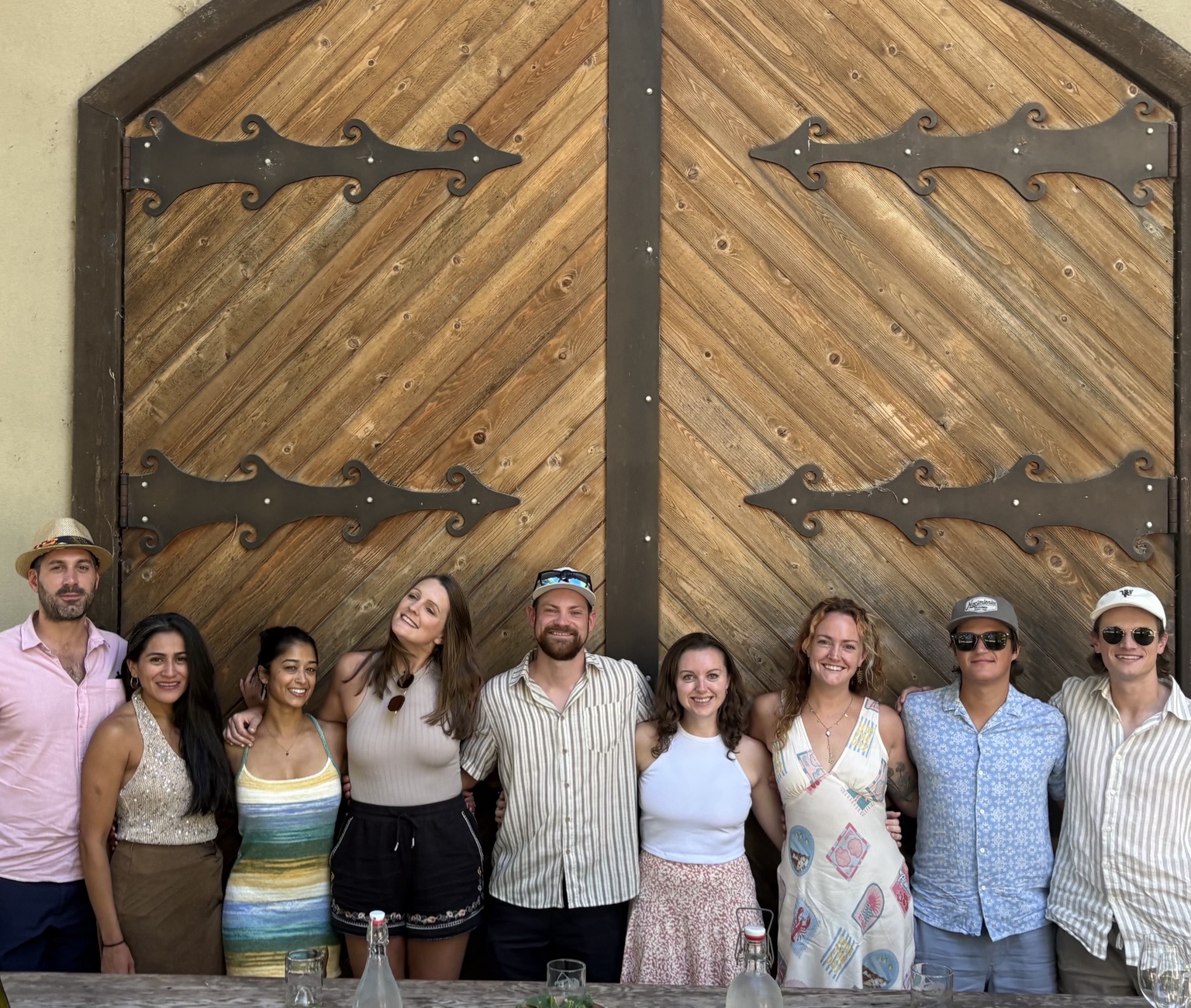 Wine tour group posing together in front of large wooden winery doors
