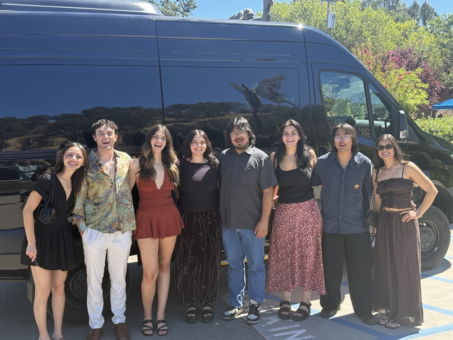 Friends smiling together beside the Black Car Adventures Mercedes Sprinter